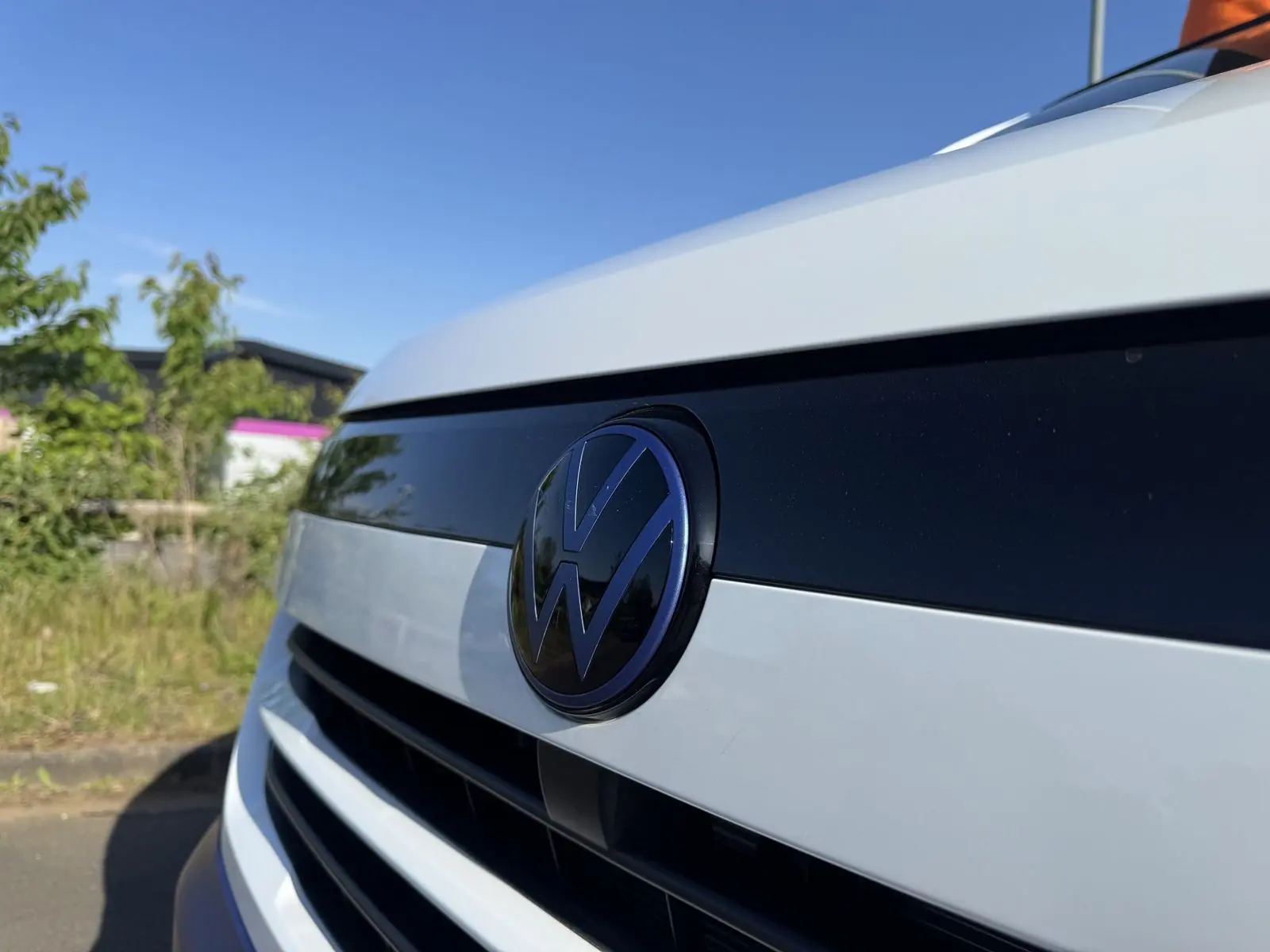 Close-up of the Volkswagen badge on the white front of the van, with the badge finished in blue to match the lower bodywork.