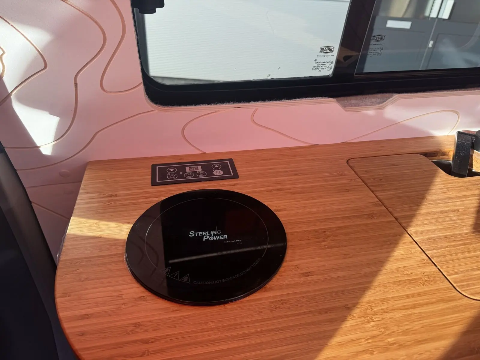 Close-up of the round black Sterling Power induction hob and its touch control panel set into the bamboo worktop.