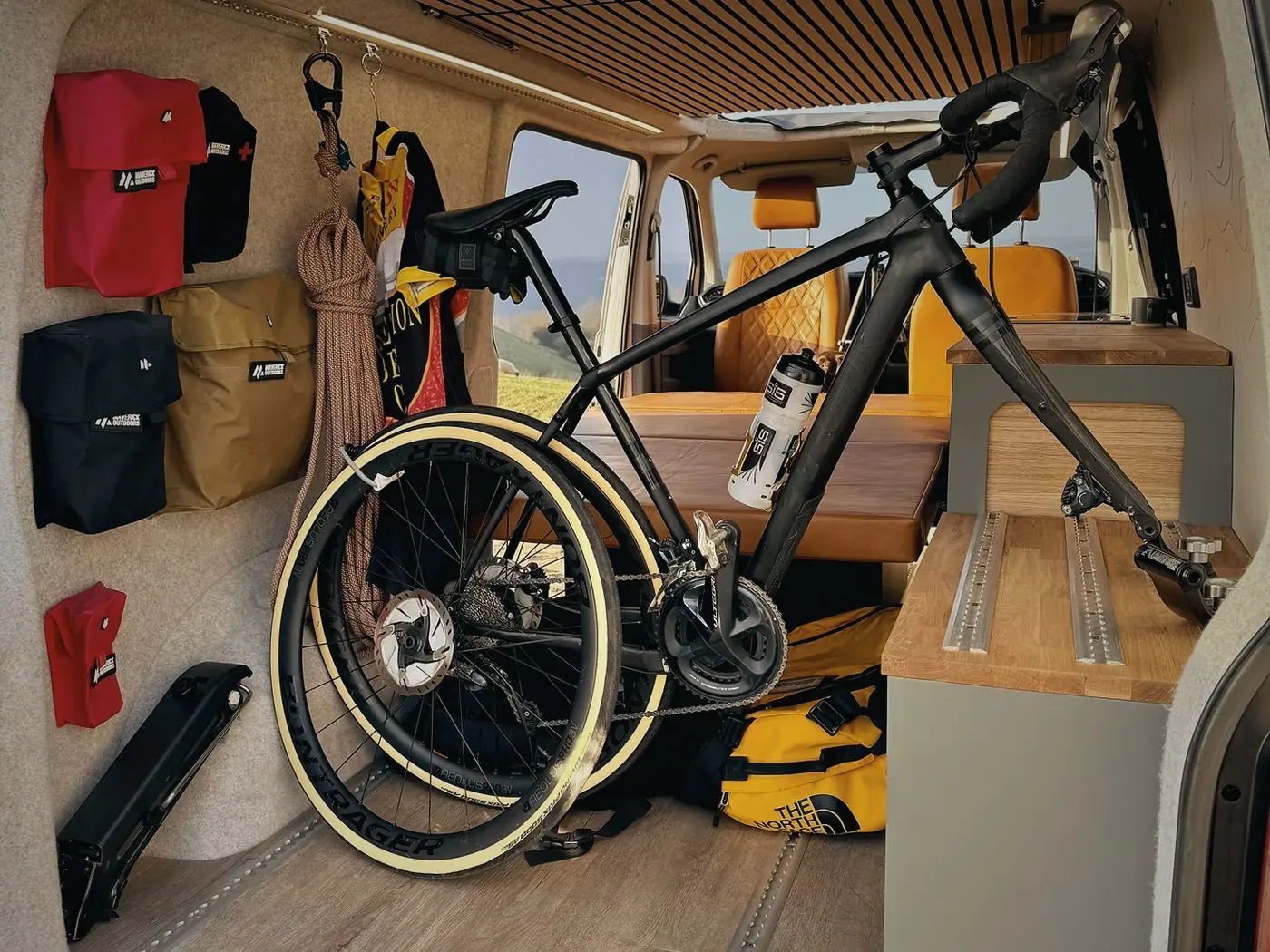 Looking into the back of a Maverick camper with a road bike mounted inside and kit bags on the wall