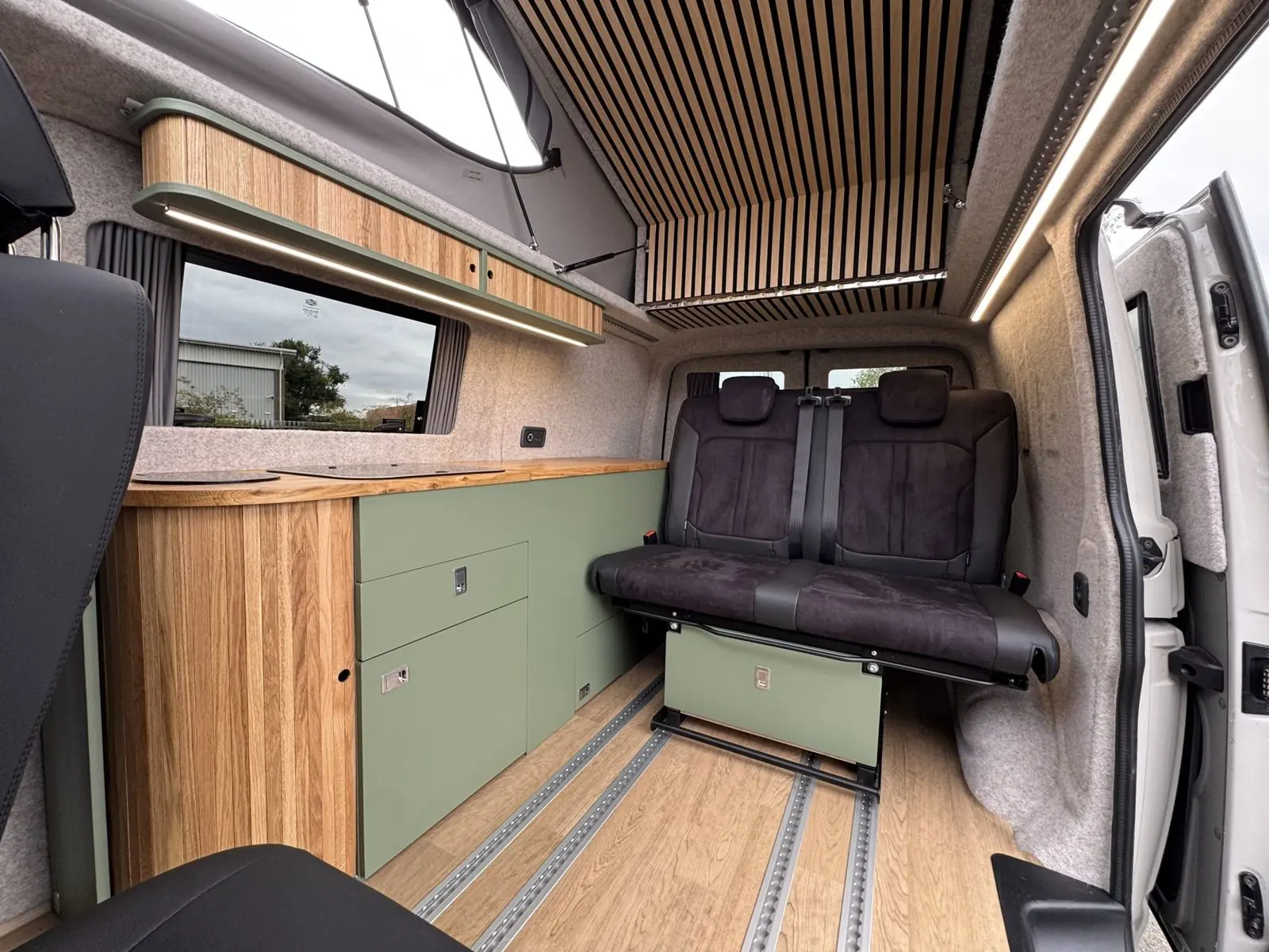 Sage green and oak kitchen with a dark bench on floor rails