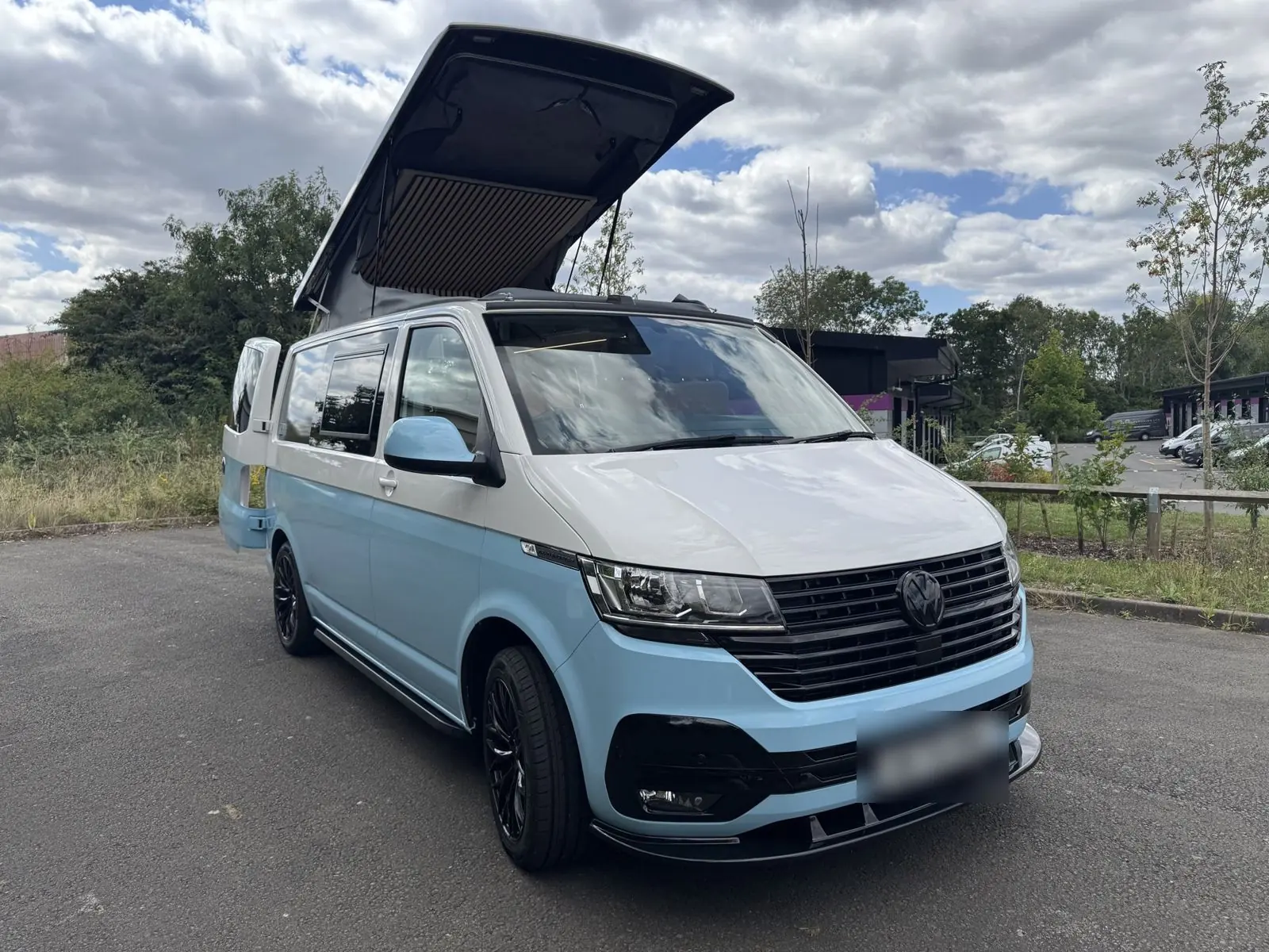 White and baby-blue two-tone camper with its pop-top raised