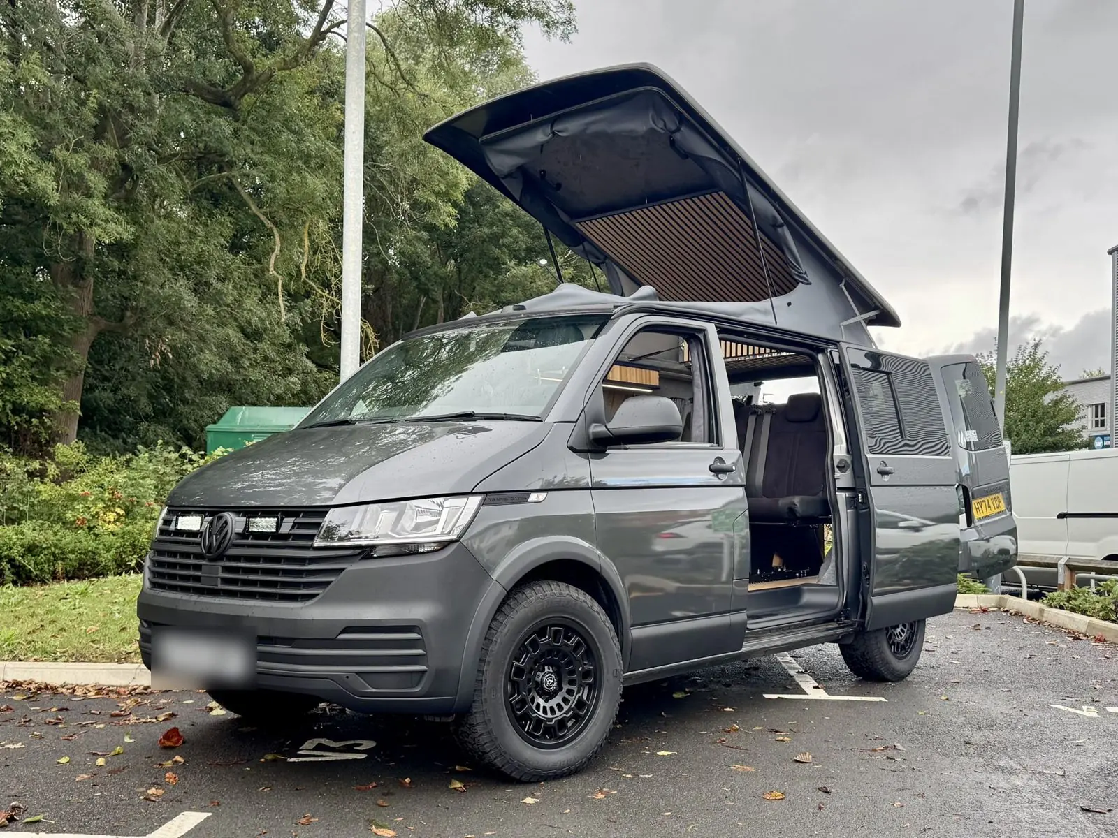 Dark grey camper on black all-terrain wheels with its pop-top raised