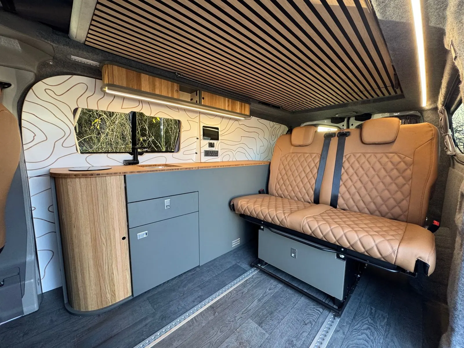 Grey kitchen with an oak end, contour wall panel and tan diamond-quilted bench