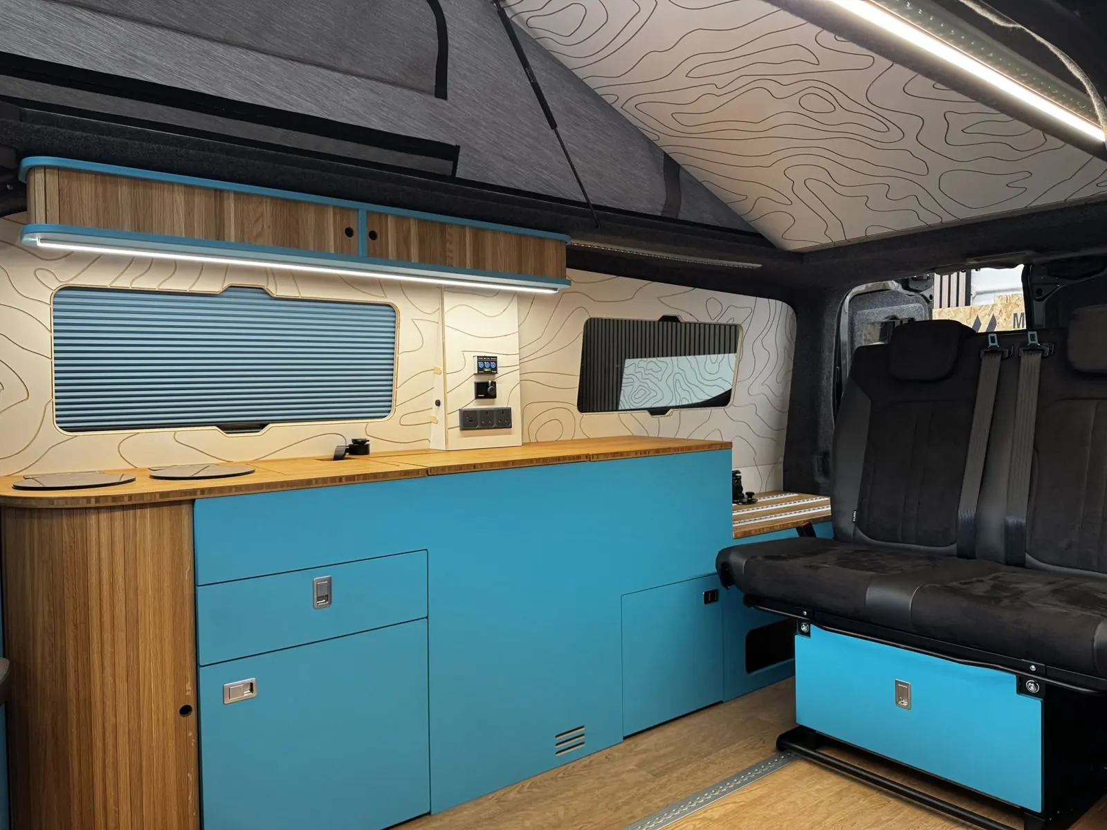 Bright blue kitchen with a blue blind, contour-print ceiling and dark bench