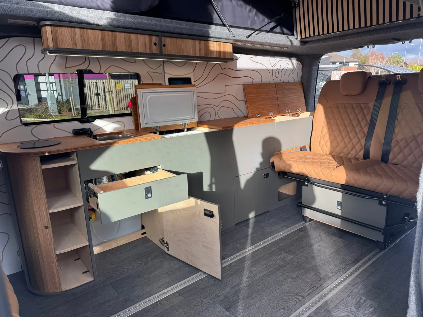 Overland module from the side door, with the bamboo lids lifted on the storage cube and the top-loading fridge open