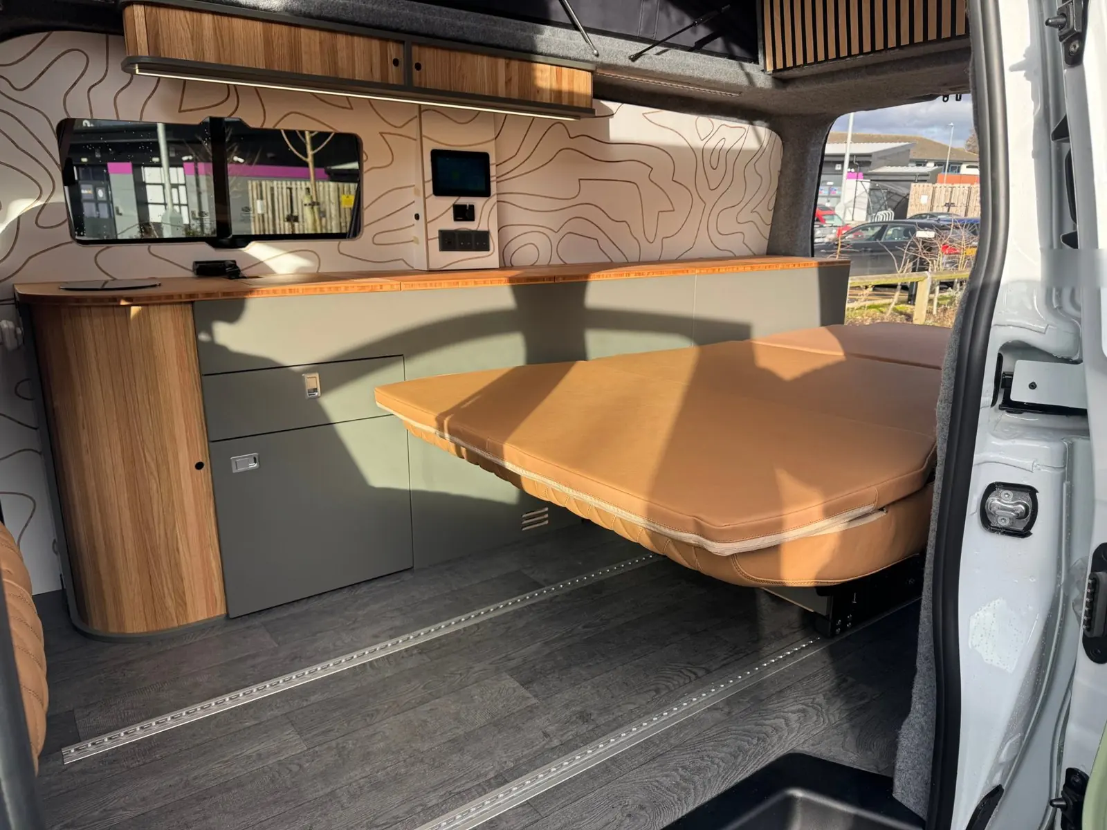 Overland layout with the rear seat folded flat into a bed beside the full-length kitchen and storage run