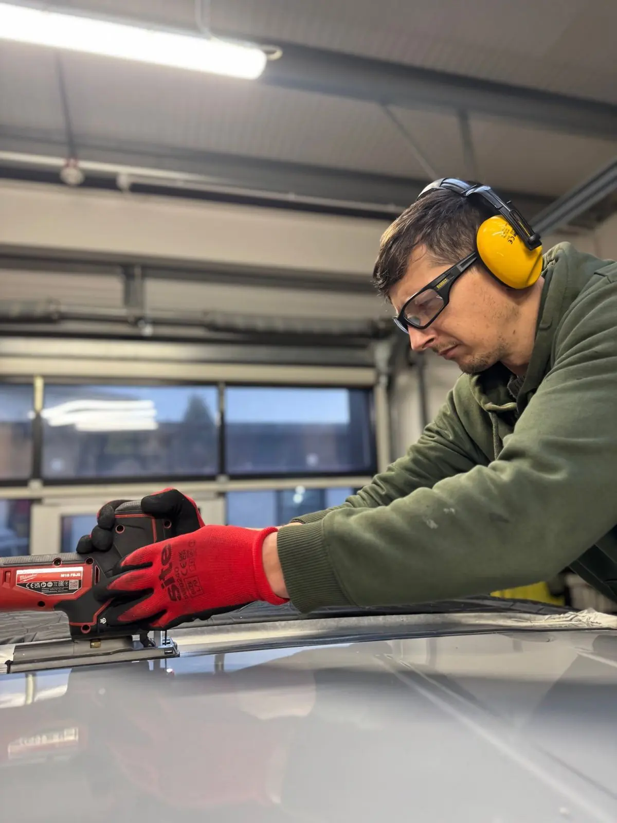 A Maverick technician in ear defenders cutting a van roof in the workshop